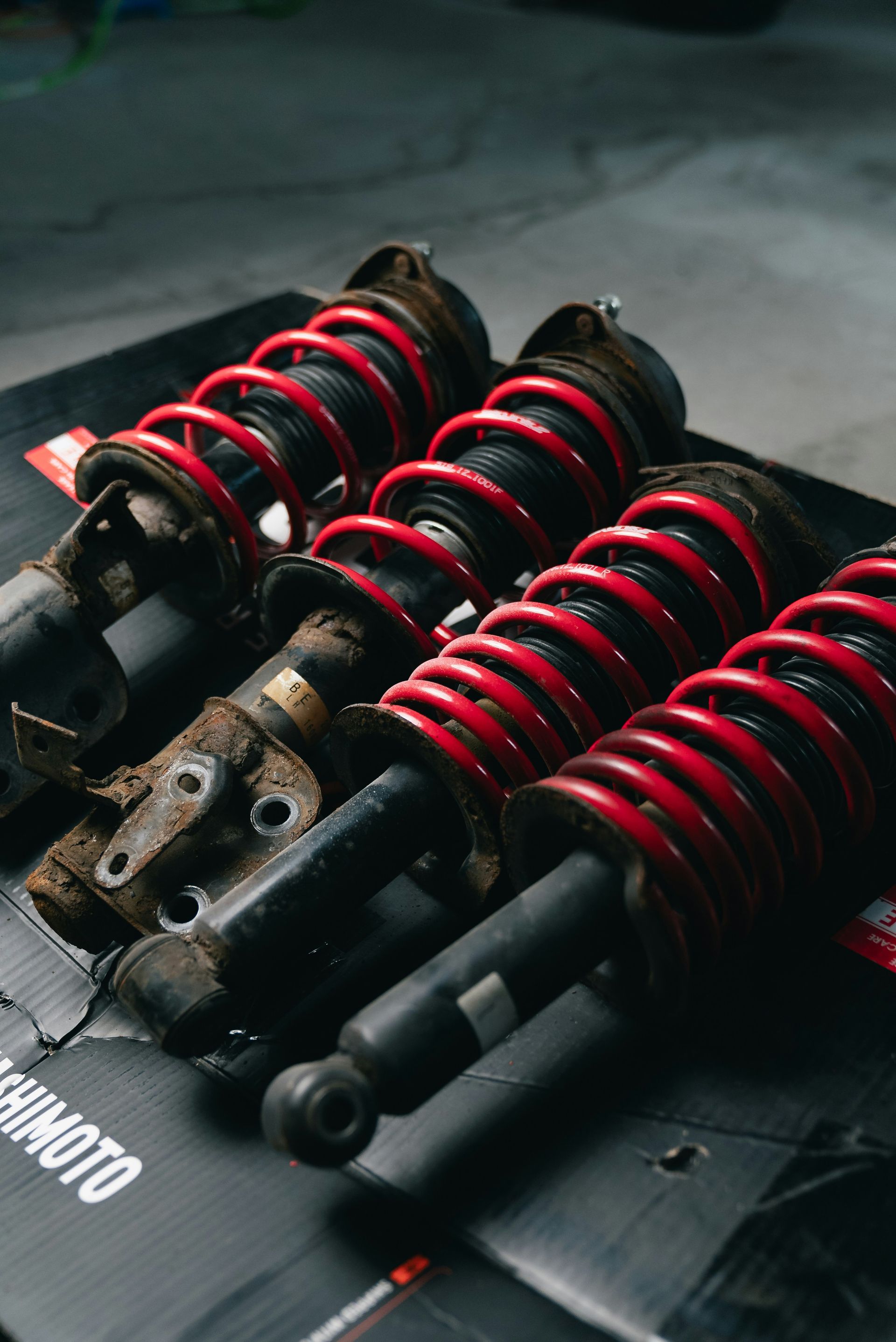 Four red coilover suspension assemblies on a black surface